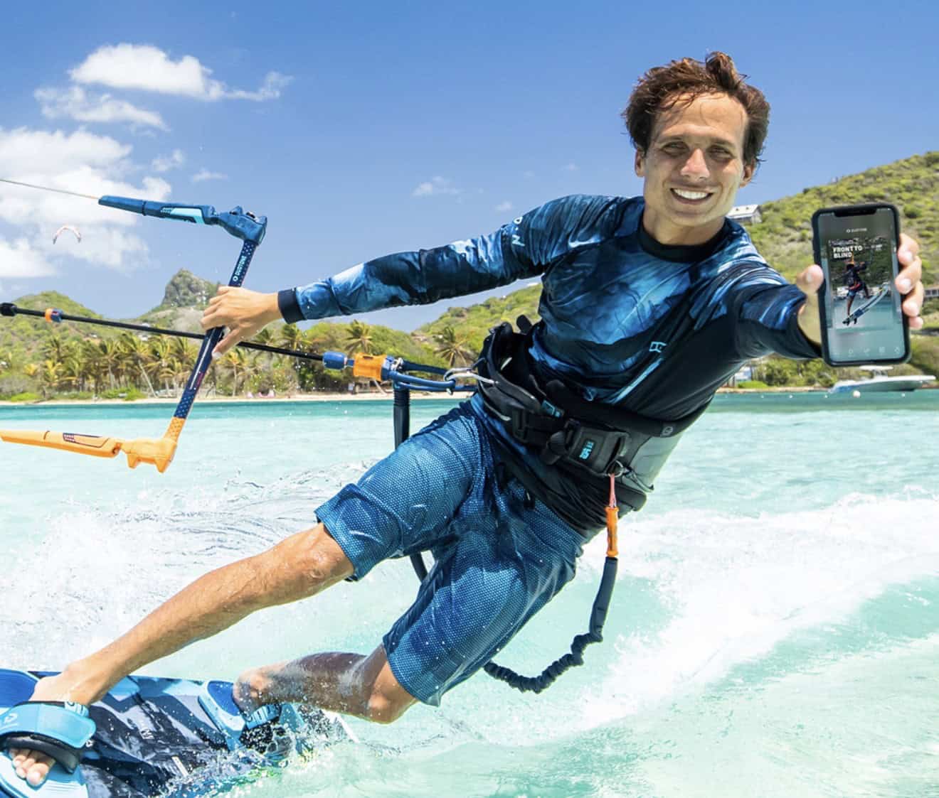 Jeremie Tronet holding the Duotone Academy app while kitesurfing on Union Island