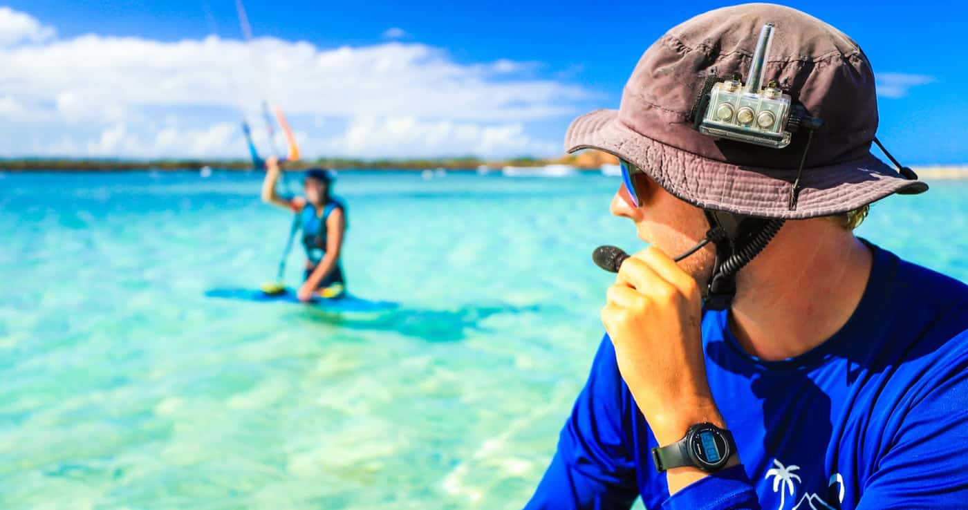 Instructor using radio coaching during a kitesurfing lesson in shallow water