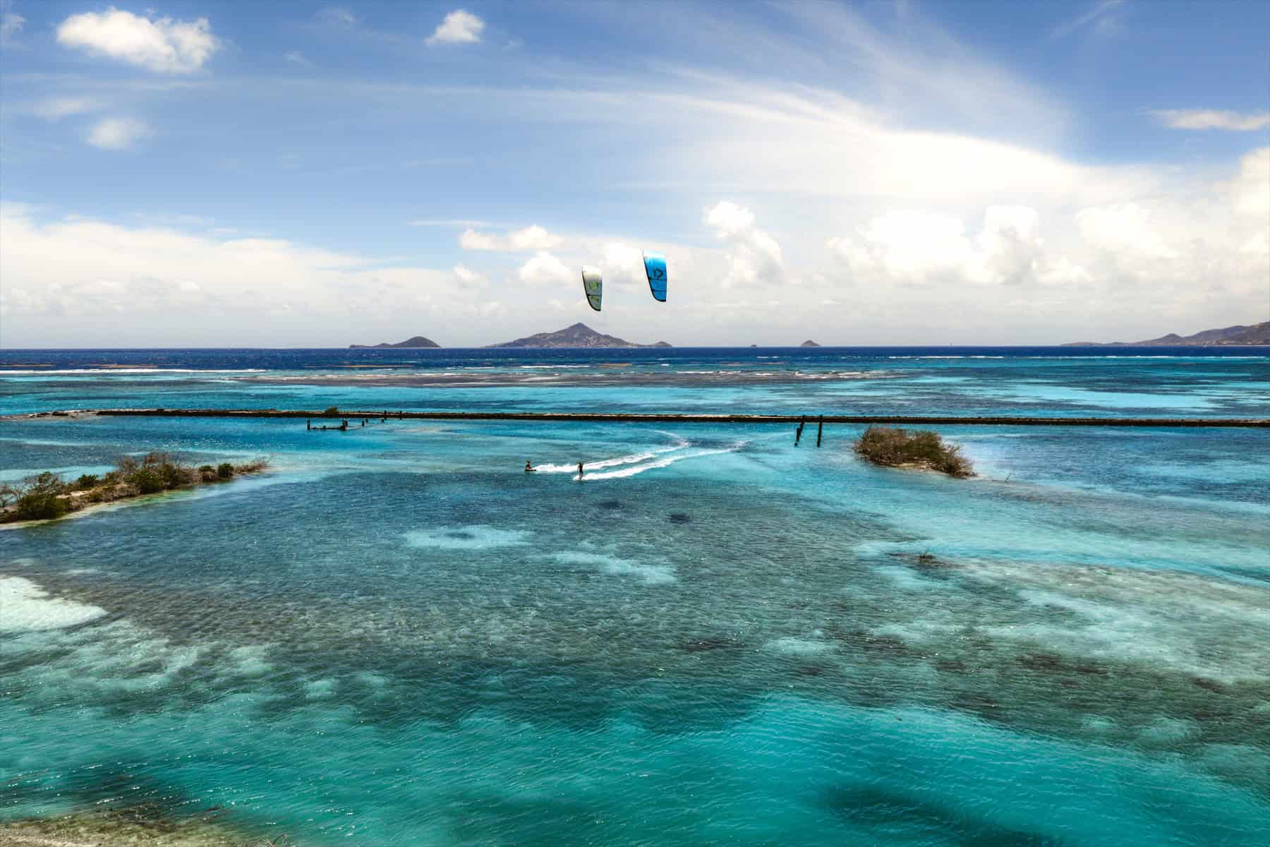 Kitesurfers crossing bright Frigate Island water on a Grenadines downwinder