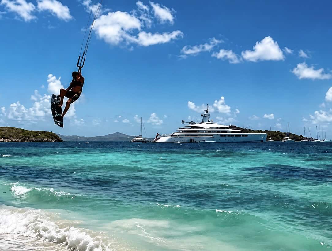 Kitesurfer riding near a superyacht anchored in the Grenadines