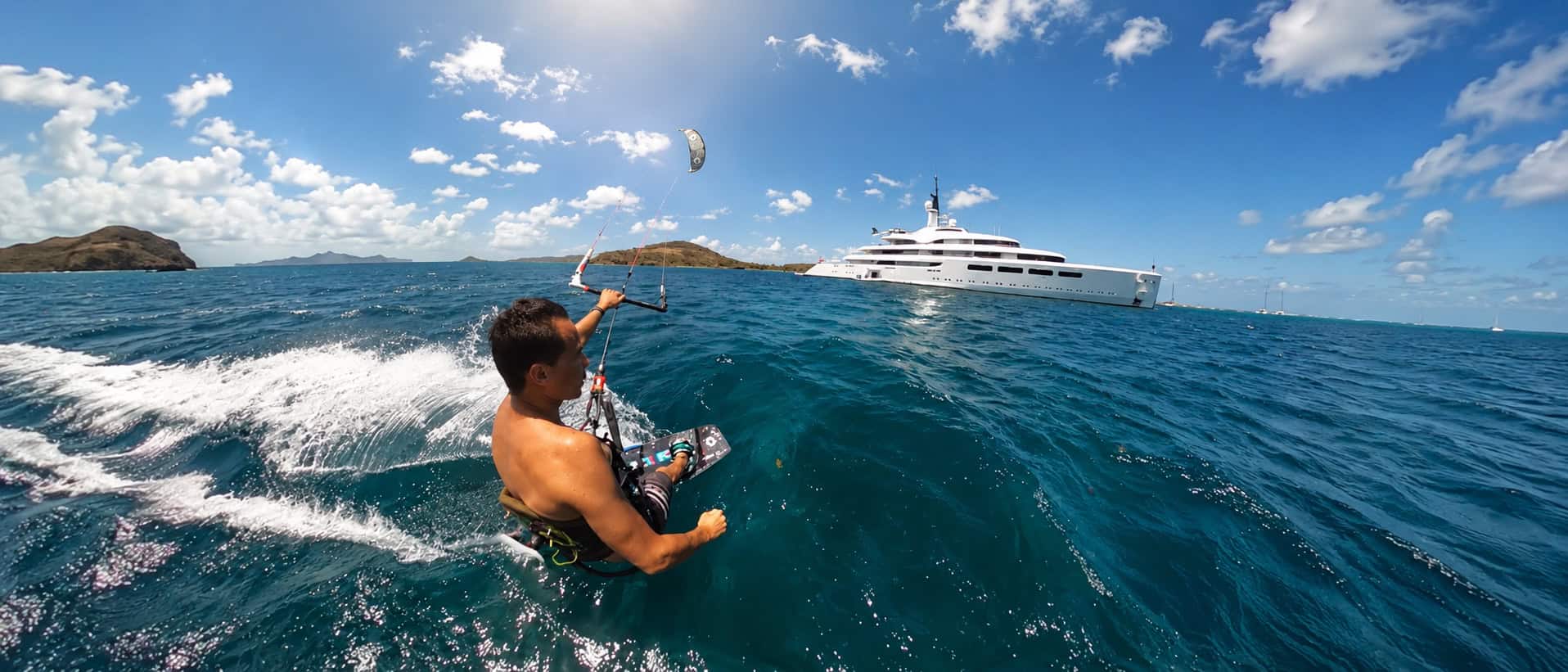Kitesurfer riding near a superyacht in the Grenadines